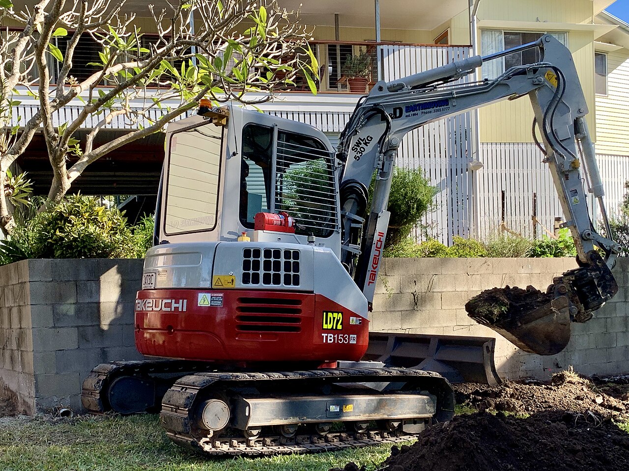 Takeuchi TB153FR excavator digging in a backyard